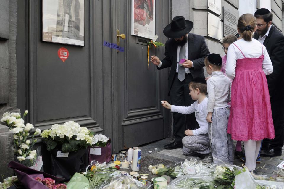 A family lights candles at the Jewish Museum, site of a shooting in central Brussels