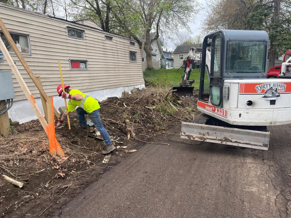 A worker with Dirty Hands Excavating and Restoration removes brush from an alley in Canton as part of Mayor William V. Sherer II's neighborhood transformation initiative. He wants to pave every alley in the city over the next four years.