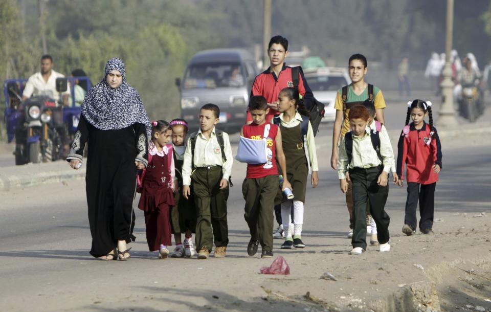 Students walk with their families to school on the first day of their new school year in Giza