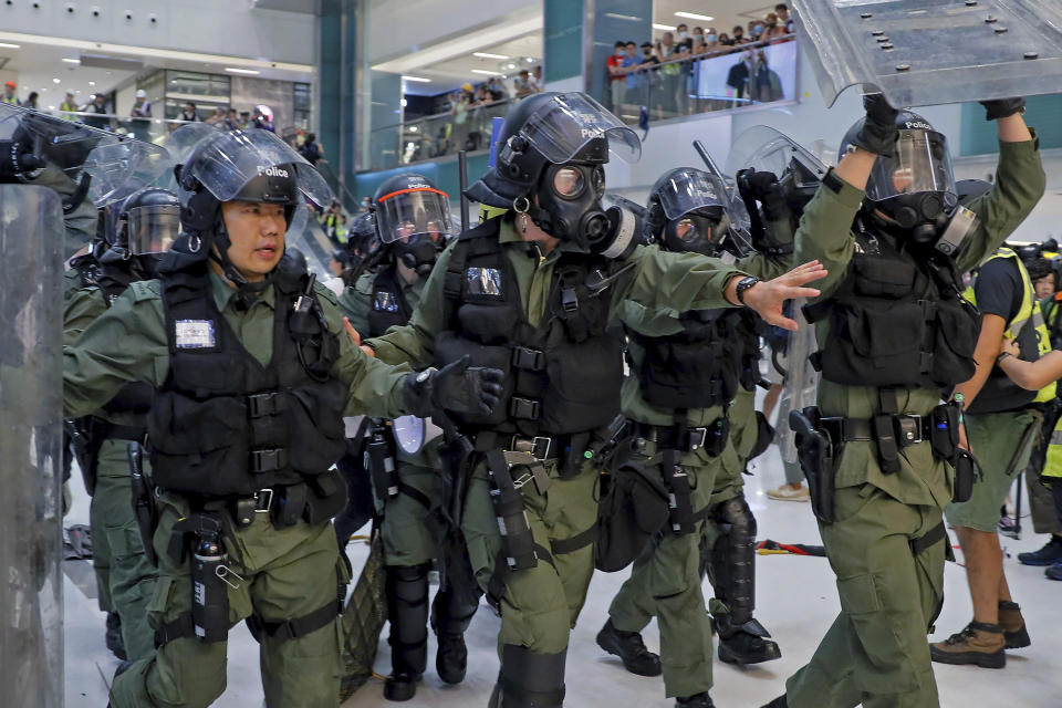 In this Sunday, July 14, 2019, photo, riot policemen move in to disperse the protesters inside a shopping mall in Sha Tin District in Hong Kong. What began as a protest against an extradition bill has ballooned into a fundamental challenge to the way Hong Kong is governed _ and the role of the Chinese government in the city’s affairs. (AP Photo/Kin Cheung)