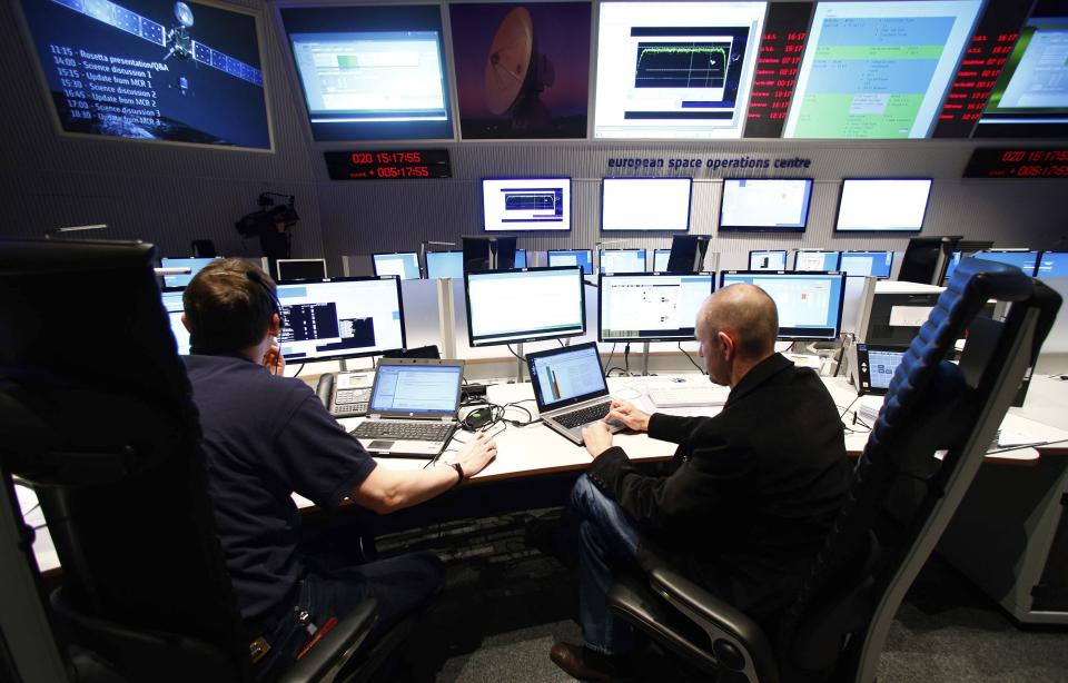 Flight engineers sit in the main control room of European Space Operations Centre (ESOC) in Darmstadt, during the Rosetta mission, January 20, 2014. Comet-chasing spacecraft Rosetta woke from nearly three years of hibernation on Monday to complete a decade-long deep space mission that scientists hope will help unlock some of the secrets of the solar system. Rosetta, which was launched by the ESA in 2004, is due to rendezvous with comet 67P/Churyumov-Gerasimenko and land a probe on it this year in an unprecedented manoeuvre. (REUTERS/Ralph Orlowski)