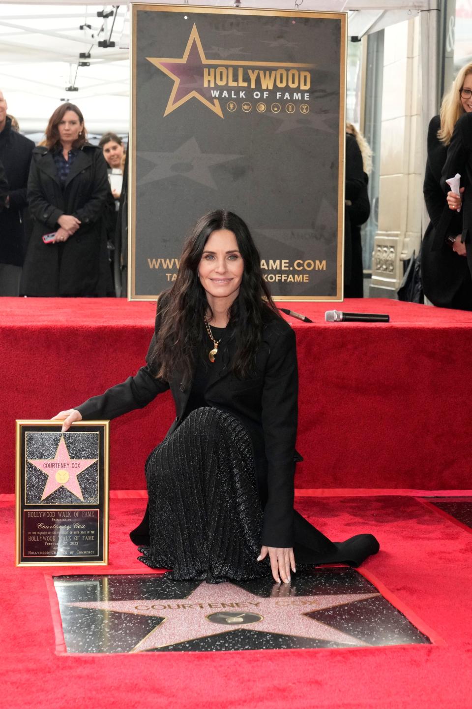 Actor and filmmaker Courteney Cox touches her star on the Hollywood Walk of Fame.