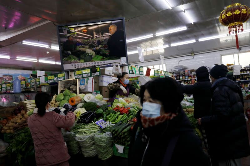 People shop for vegetables at a market in Beijing