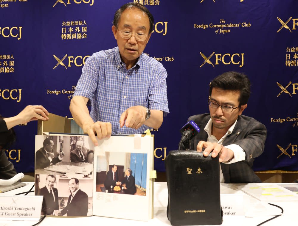 Members of the National Network of Lawyers Against Spiritual Sales, Hiroshi Yamaguchi, left, and Yasuo Kawai, right, display a history book of the Unification Church and the group's Holy book at a press conference in Tokyo on July 29, 2022. <span class="copyright">Yoshio Tsunoda—AFLO/Shutterstock</span>