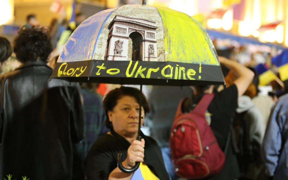 People holding banners and Ukrainian flags gather around parliament building to protest against Russia's missile attacks in Tbilisi - Anadolu