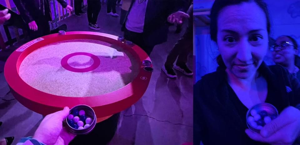 Kirsten Acuna holds a tin full of marbles in front of a table with a circle in it at Netflix's Squid Game: The Trials event