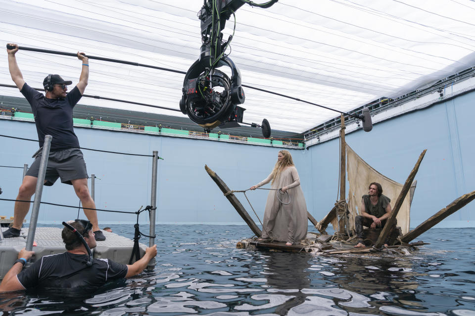 This image released by Amazon Studios shows Morfydd Clark, center, and Charlie Vickers, right, on the set of "The Lord of the Rings: The Rings of Power." (Amazon Studios via AP)