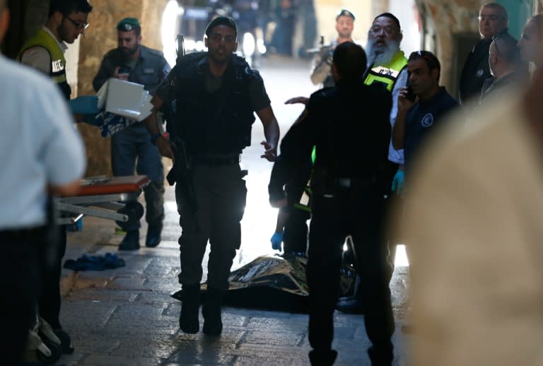 Israeli security forces and emergency personnel stand next to the covered body of a Palestinian man who stabbed and seriously wounded an Israeli border policeman before being killed by Israeli officers in Jerusalem on November 29, 2015