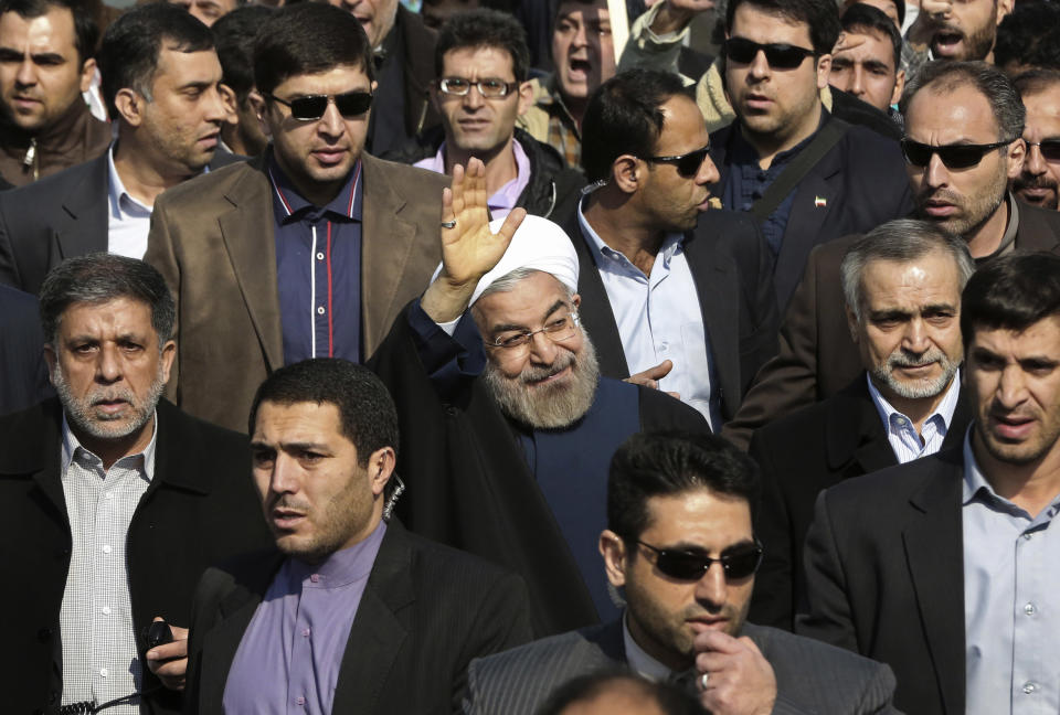 Escorted by his bodyguards, Iranian President Hassan Rouhani, center, waves to his well wishers as he attends an annual rally commemorating the anniversary of the 1979 Islamic revolution, in Tehran, Iran, Tuesday, Feb. 11, 2014. Rouhani on Tuesday called for "fair and constructive" nuclear talks with world powers as the nation marked the anniversary of the 1979 Islamic revolution with massive rallies, complete with anti-American and anti-Israeli chants. Tuesday marks the 35th anniversary of the revolution that toppled the pro-U.S. Shah Mohammad Reza Pahlavi and brought Islamists to power. Hossein, brother of the President Rouhani accompanies him at right. (AP Photo/Vahid Salemi)