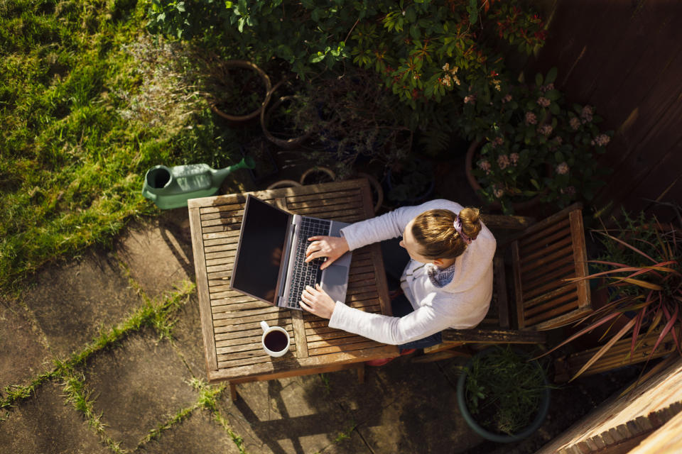 UK, Essex, Harlow, elevated view of a woman working from home in her garden using a laptop computer