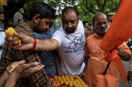 People distribute sweets as they celebrate after the government scrapped the special status for Kashmir, in New Delhi