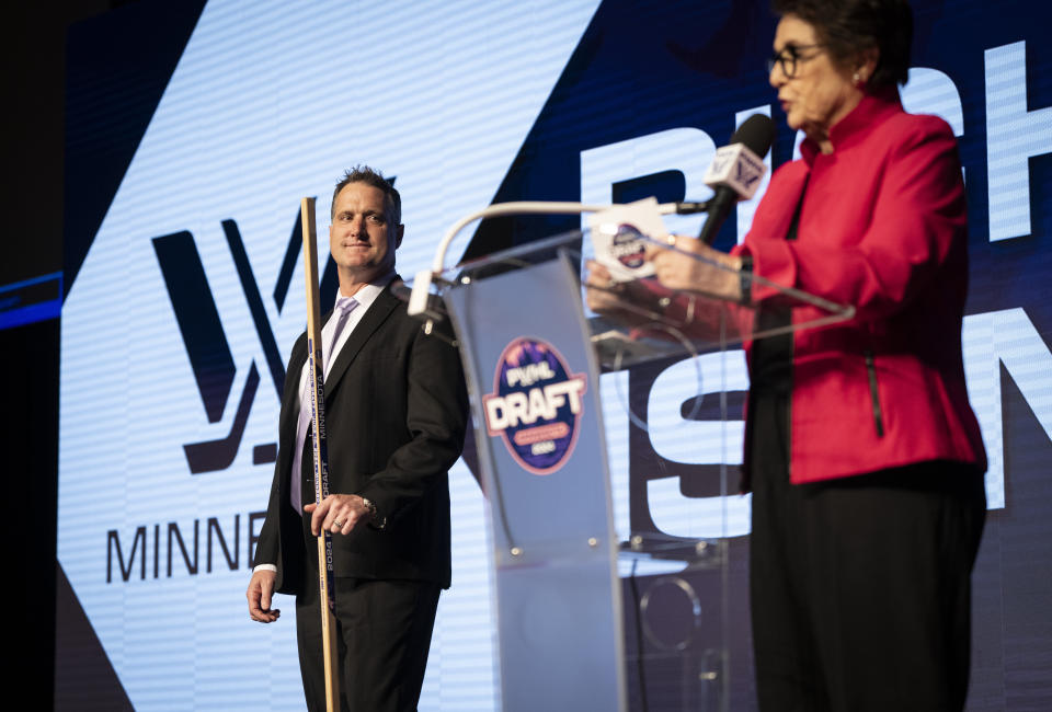Minnesota head coach Ken Klee, left, listens as tennis great Billie Jean King, right, reads Minnesota's first-round pick Claire Thompson, who was not present, during the PWHL hockey draft in St. Paul, Minn., Monday, June, 10, 2024. (Renee Jones/Star Tribune via AP)