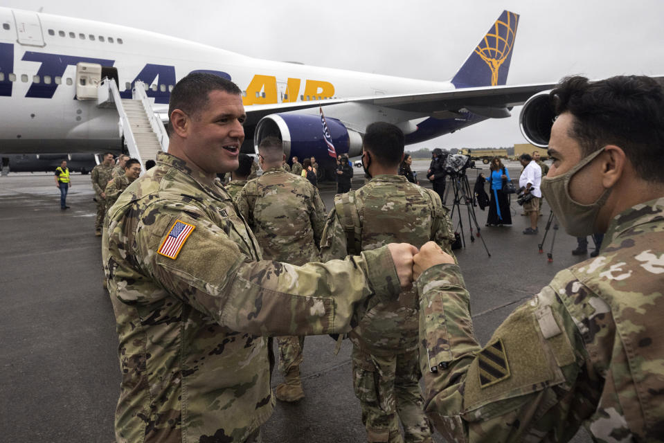 A line of soldiers with the U.S. Army's 87th Division Sustainment Support Battalion, 3rd Division Sustainment Brigade, right, get a fist bump from members of the command staff during their deployment to Europe, Friday, March 11, 2022, at Hunter Army Airfield in Savannah, Ga. The unit is attached to the Army's 3rd Infantry Division out of Fort Stewart, Ga., and will join the 3,800 troops already deployed in support of NATO in Eastern Europe. (AP Photo/Stephen B. Morton)