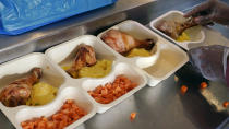 Volunteer Ibrahim Bahrr places freshly made chicken into individual meal packaging at Community Servings, which prepares and delivers scratch-made, medically tailored meals to individuals & families living with critical & chronic illnesses, Tuesday, Jan. 12, 2021, in the Jamaica Plain neighborhood of Boston. Food is a growing focus for insurers as they look to improve the health of the people they cover and cut costs. Insurers first started covering Community Servings meals about five years ago, and CEO David Waters says they now cover close to 40%. (AP Photo/Charles Krupa)