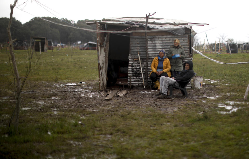 Una familia se sienta afuera de una casa improvisada en un campamento invadido ilegalmente en Guernica, provincia de Buenos Aires, Argentina, el domingo 27 de septiembre de 2020. Argentina reportó el miércoles que la pobreza subió al 40,9% en el primer semestre del año, un aumento del 5,4% respecto de igual período del año pasado. (Foto AP/Natacha Pisarenko)