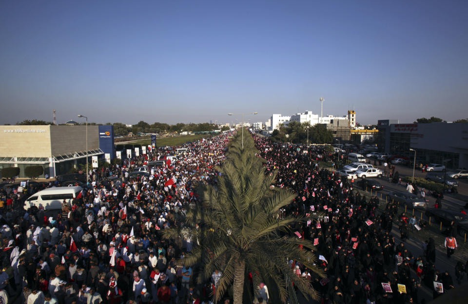 Tens of thousands of Bahraini pro-democracy protesters wave signs and national flags during a march along a divided four-lane highway near Barbar, Bahrain, west of the capital of Manama, on Saturday, Feb. 15, 2014. Protesters called for the long-serving prime minister, Sheik Khalifa bin Salman Al Khalifa, to step down and for democracy in the Gulf island kingdom. (AP Photo/Hasan Jamali)