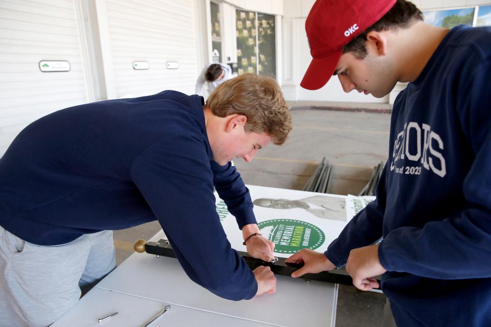 Cole Corley, right, and Kyle McLaughlin work on banners for the Oklahoma City Marathon on March 25.