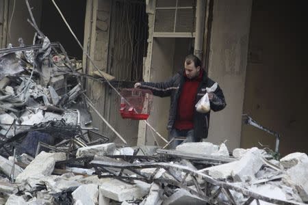 A man carries a bird cage after air strikes by pro-Syrian government forces in the rebel-held Al-Shaar nighbourhood of Aleppo, Syria February 4, 2016. REUTERS/Abdalrhman Ismail