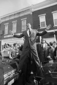 (Original Caption) Republican Presidential candidate Ronald Reagan stands on the bumpers of two cars as he tries to get a better view of the crowd, as he visits his birthplace of Tampico, Illinois. Reagan is also standing outside the apartment where he was born, right above the First National Bank.