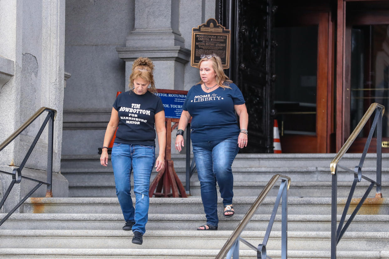 Sandra Weyer (left) and another woman wearing a T-shirt printed Moms for Liberty descend the steps from the Pennsylvania State Capitol.