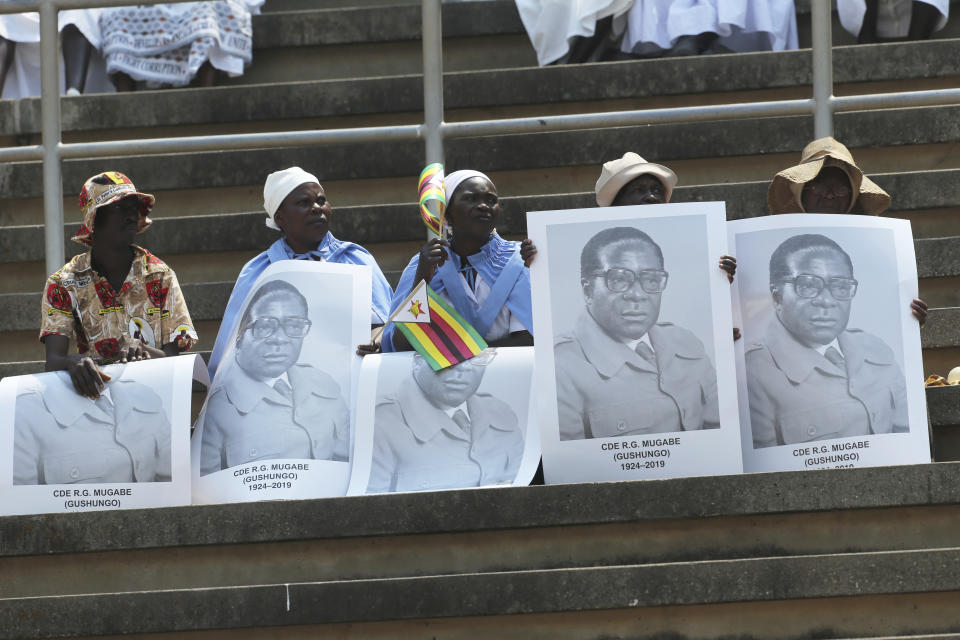 Supporters the late former Zimbabwean leader, Robert Mugabe carry his portrait as his remains arrive at the National Sports stadium during a funeral procession in Harare, Saturday, Sept, 14, 2019. African heads of state and envoys are gathering to attend a state funeral for Mugabe, whose burial has been delayed for at least a month until a special mausoleum can be built for his remains. (AP Photo/Tsvangirayi Mukwazhi)