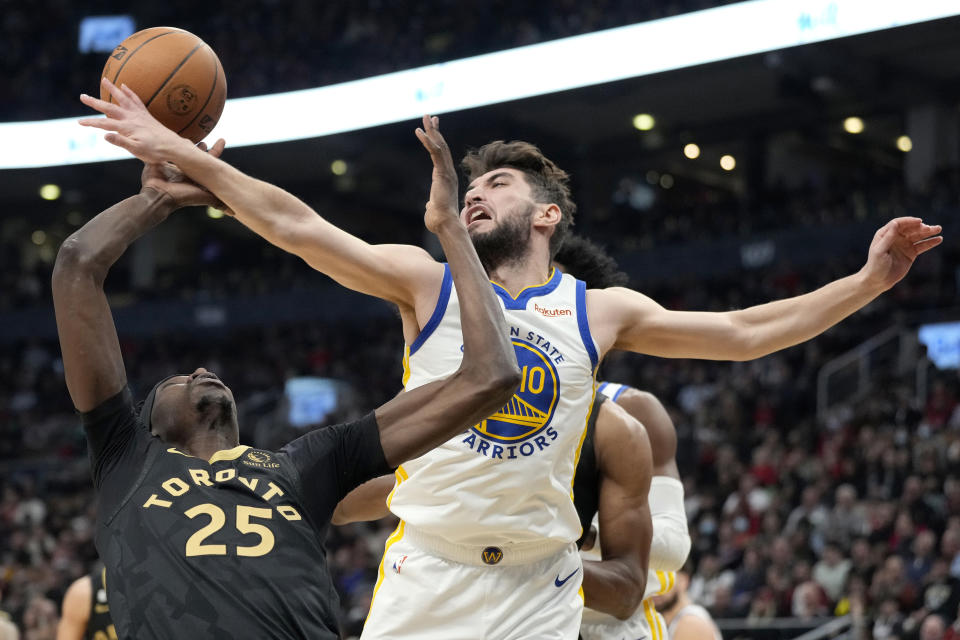 Golden State Warriors guard Ty Jerome (10) tries to swat the ball away from Toronto Raptors forward Chris Boucher (25) during first-half NBA basketball game action in Toronto, Sunday, Dec. 18, 2022. (Frank Gunn/The Canadian Press via AP)