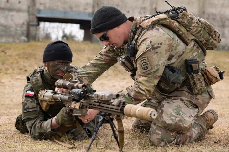 A paratrooper assigned to the 3rd Brigade Combat Team, 82nd Airborne Division, introduces a Polish soldier to an M110A1 squad designated marksman rifle during a Feb. 28, 2022, training event in Zamość, Poland.