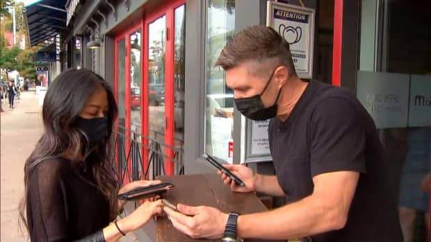 Mike Deas-Dawlish, right, checks a customer's vaccine card outside Jam Cafe in Vancouver on Sept. 13, 2021. (CBC Radio-Canada - image credit)