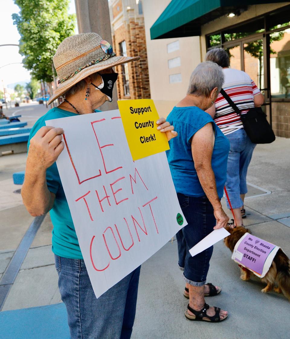 Linda McCrea, left, holds a sign outside the Shasta County Elections Office on Friday, June 10, 2022, in support of Clerk Cathy Darling Allen and elections worker tallying the June 7 results.