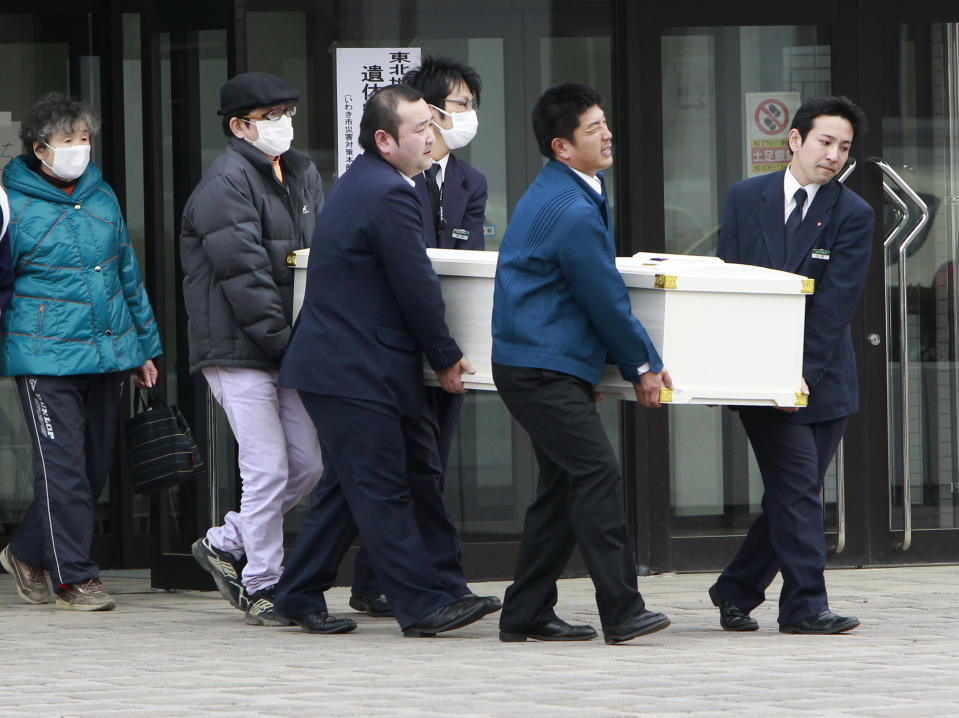 FILE - A relative watches as a coffin of a tsunami victim is carried from an emergency morgue in Iwaki, Japan, on March 14, 2011, three days after a giant quake and tsunami struck the country's northeastern coast. The 2011 quake, tsunami and nuclear meltdown in northern Japan provides a glimpse of what Turkey and Syria could face in the years ahead. No two events are alike, but the recent disaster resembles Japan's in the sheer enormity of the psychological trauma, of the loss of life and of the material destruction. (AP Photo/Mark Baker, File)