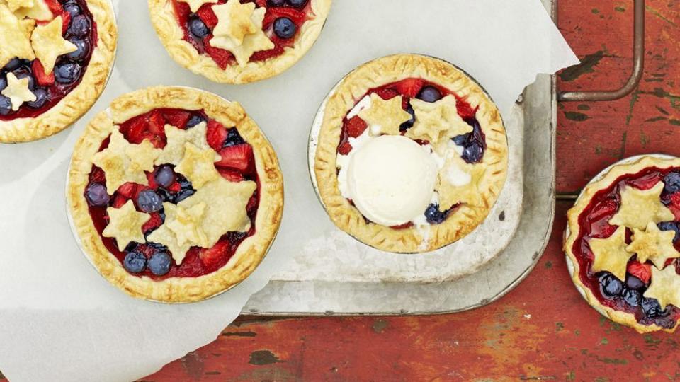 mini stars berry pies on a parchment paper lined metal serving tray on a red painted wooden table