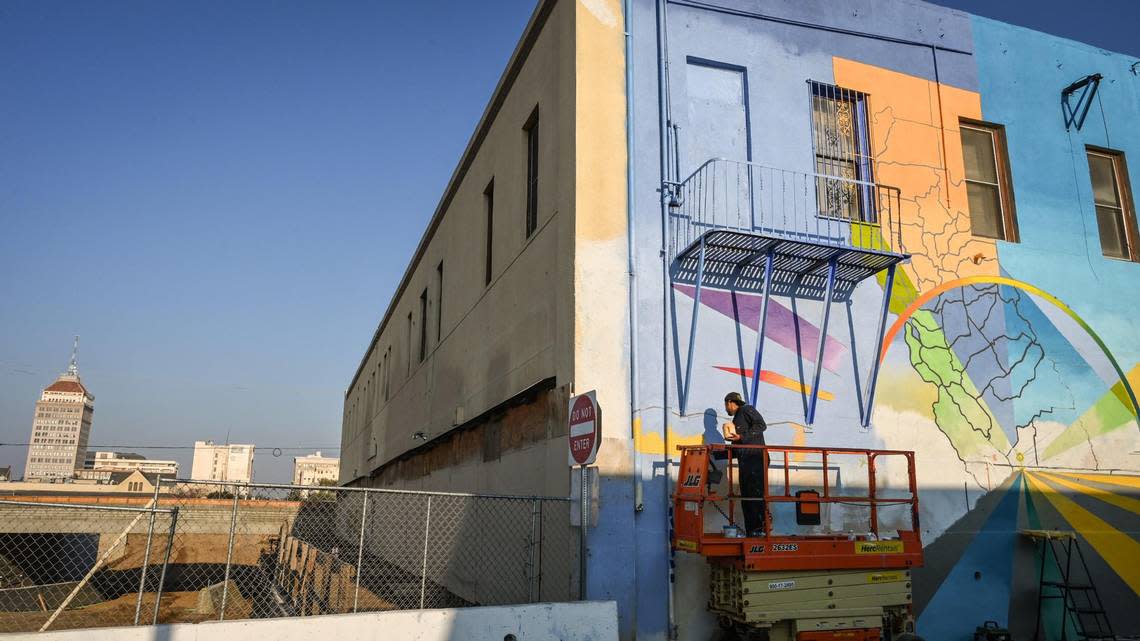 Fresno muralist Mauro Carrera works on a mural on a historic Chinatown building on China Alley in downtown Fresno on Friday, Dec. 16, 2022. The project is in conjunction with the Fresno Arts Council and the California High-Speed Rail Authority.