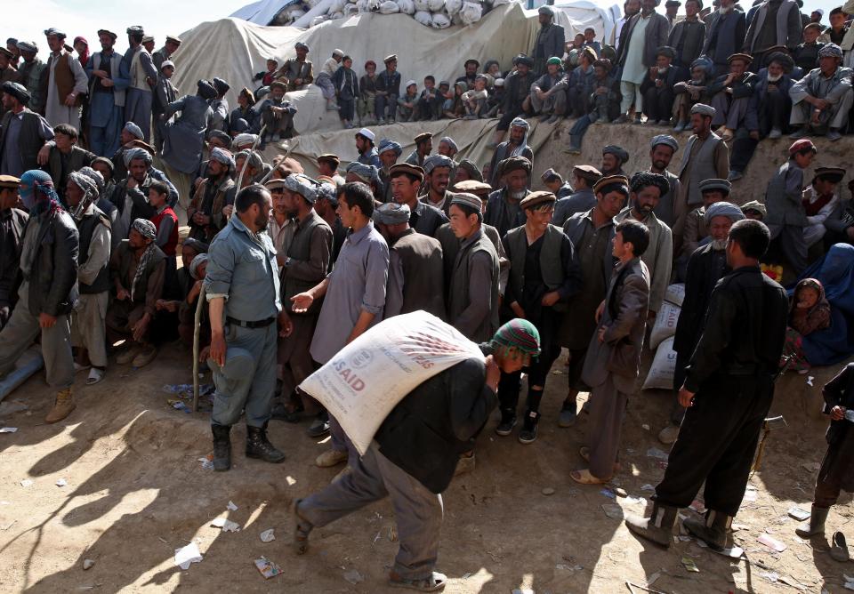 Survivors wait to receive food donations near the site of Friday's landslide that buried Abi-Barik village in Badakhshan province, northeastern Afghanistan, Tuesday, May 6, 2014. Authorities tried to help families displaced by the torrent of mud that swept through Abi-Barik village after hundreds were killed. (AP Photo/Massoud Hossaini)