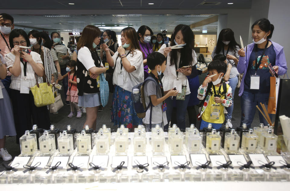 Participants smell perfume at a duty free shop during a mock trip abroad at Taipei Songshan Airport in Taipei, Taiwan, Tuesday, July 7, 2020. Dozens of would-be travelers acted as passengers in an activity organized by Taiwan’s Civil Aviation Administration to raise awareness of procedures to follow when passing through customs and boarding their plane at Taipei International Airport. (AP Photo/Chiang Ying-ying)