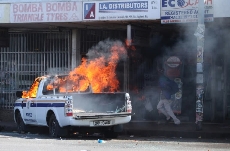 A man runs past Zimbabwean police car allegedly set ablaze by supporters of the opposition party Movement for Democratic Change Tsvangirai faction (MDC-T) during a march against police brutality in Harare on August 24, 2016