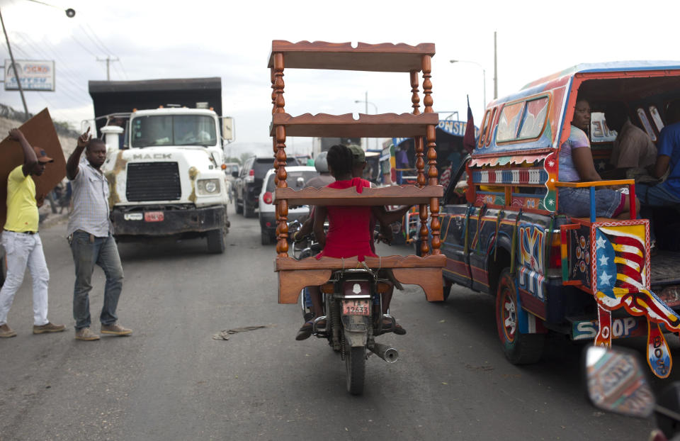 A motorcycle taxi passenger transports furniture through a busy street in Port-au-Prince, Haiti, Thursday, Sept. 20, 2018. (AP Photo/Dieu Nalio Chery)