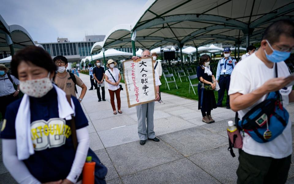 An elderly man holds up a sign that reads 'Don't let children cry because of adults' war' as he queues in line to pray at Peace Memorial Park in Hiroshima - DAI KUROKAWA/EPA-EFE/Shutterstock /Shutterstock