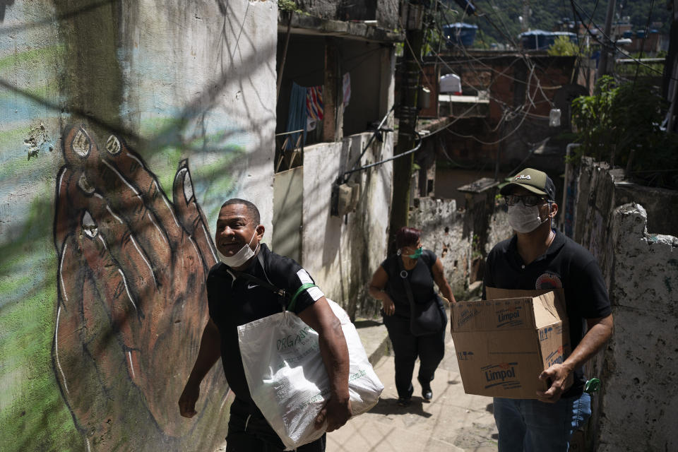 Volunteers carry packages with soap and detergent to be distributed in an effort to avoid the spread of the new coronavirus in the Rocinha slum in Rio de Janeiro, Brazil, Tuesday, March 24, 2020. (AP Photo/Leo Correa)