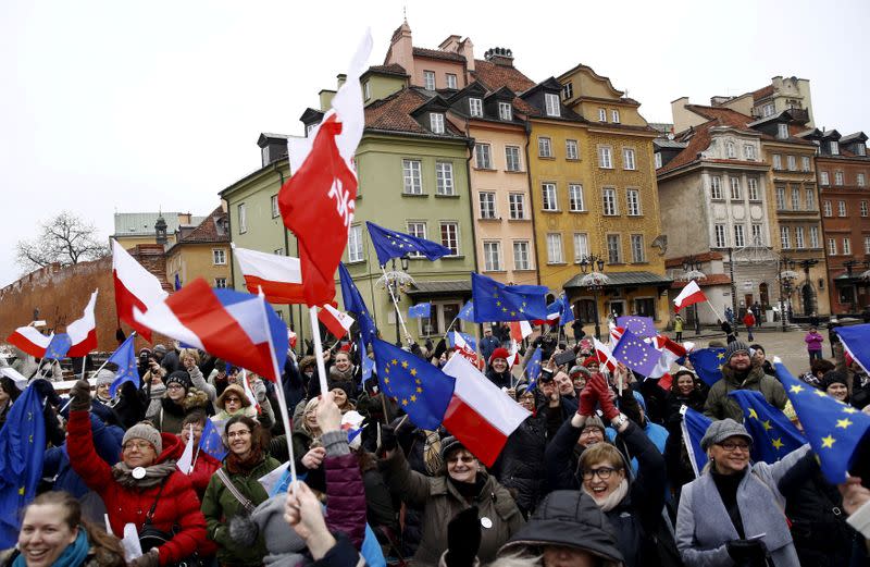 FILE PHOTO: People hold EU and Polish flags as they gather during a pro-democracy demonstration at the Old Town in Warsaw