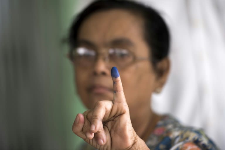 A woman shows her finger, which was inked after she cast her vote in a by-election, in a polling station in Yangon, Myanmar