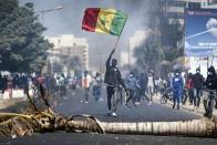 A demonstrator waves a Senegalese national flag during protests in support of main opposition leader and former presidential candidate Ousmane Sonko in Dakar, Senegal, Wednesday, March 3, 2021. Sonko was arrested Wednesday on charges of disturbing the public order after hundreds of his supporters clashed with police while he was heading to the court to face rape charges. (AP Photo/Leo Correa)