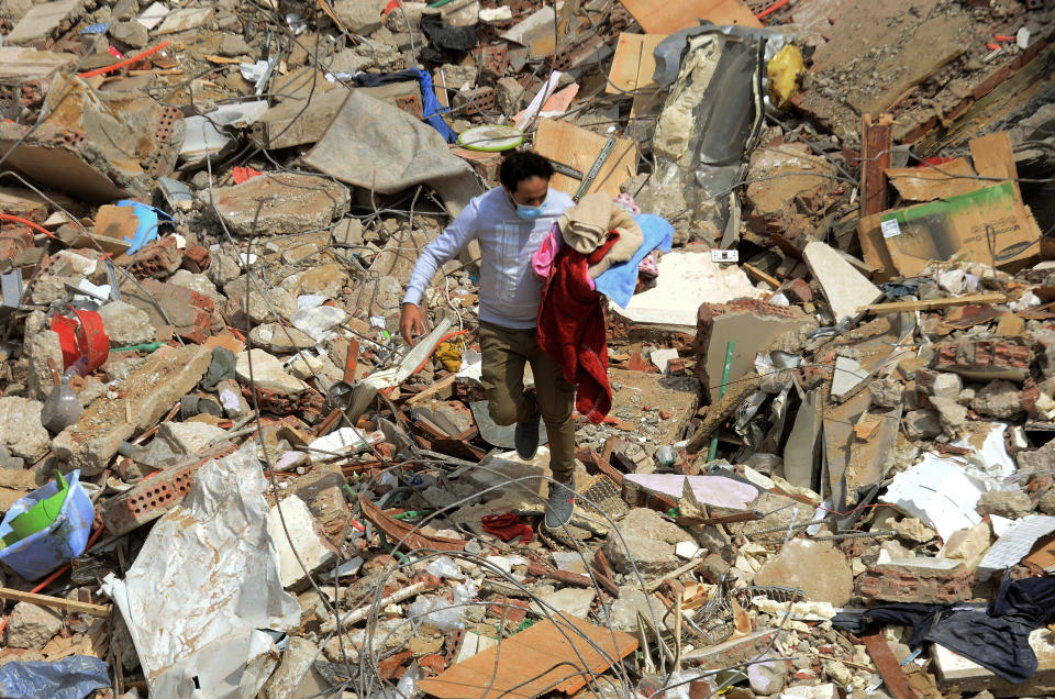 A man walks on the rubble of a collapsed apartment building in the el-Salam neighborhood, in Cairo, Egypt, Saturday, March 27, 2021. A nine-story apartment building collapsed in the Egyptian capital early Saturday, killing at several and injuring about two dozen others, an official said. (AP Photo/Tarek wajeh)
