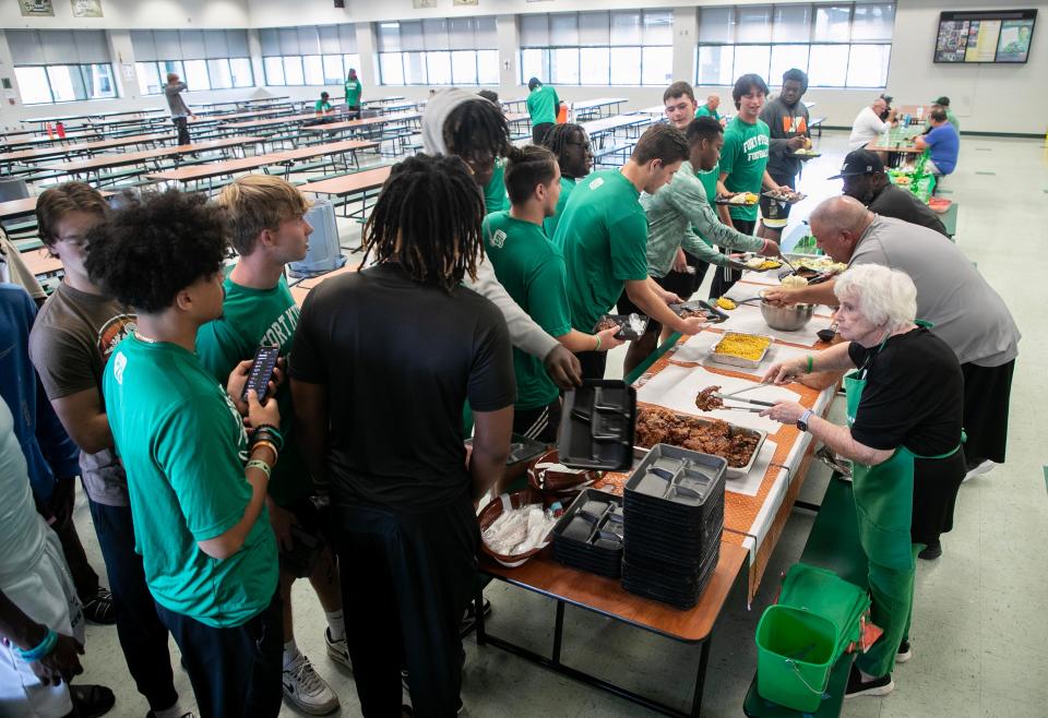 Fort Myers High School football players line up for their pre-game meal on Thursday, Oct. 19, 2023, at Fort Myers High School. Volunteers make a meal for the students to eat before each game.