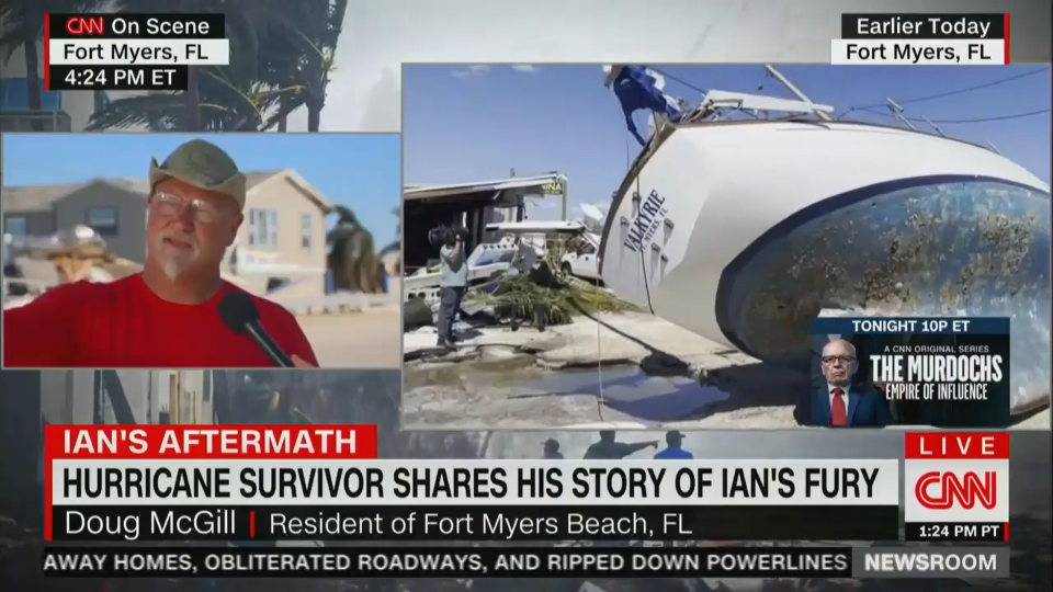 Doug McGill's sailboat is shown lying in the middle of a road as he is interviewed on CNN.