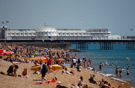 FILE PHOTO - Visitors enjoy the sunshine on the beach by Brighton Pier in Brighton, Britain, June 28, 2018. REUTERS/Henry Nicholls