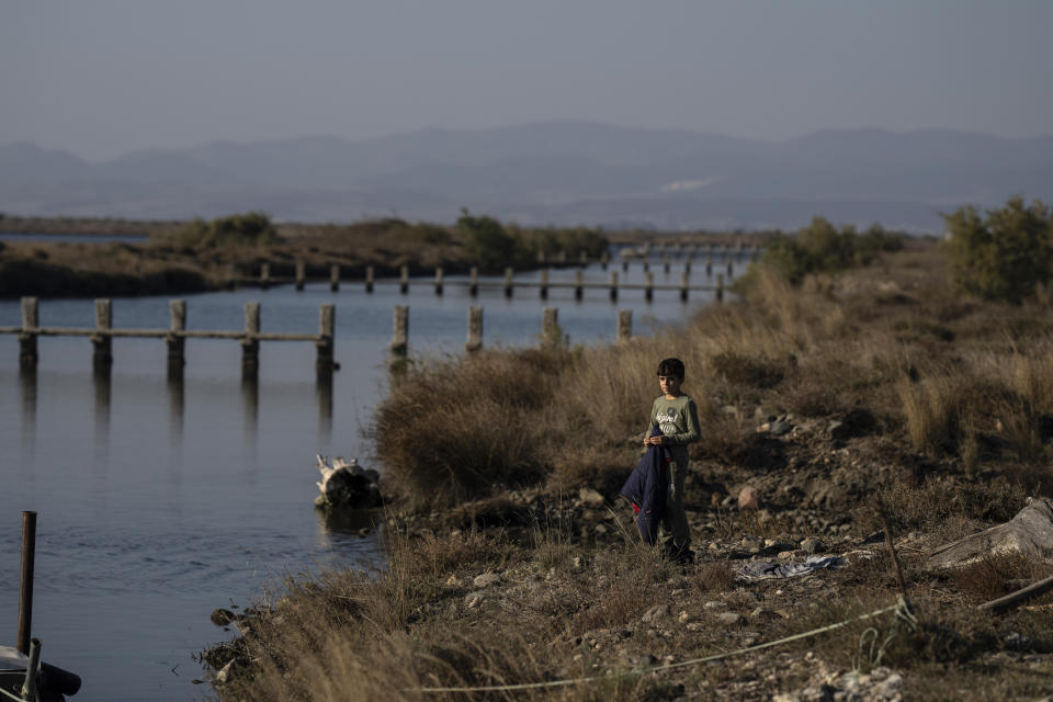 A boy look on along the Evros River that forms a natural border between Greece and Turkey, on Sunday, Oct. 30, 2022. Greece is planning a major extension of a steel wall along its border with Turkey in 2023, a move that is being applauded by residents in the border area as well as voters more broadly. (AP Photo/Petros Giannakouris)