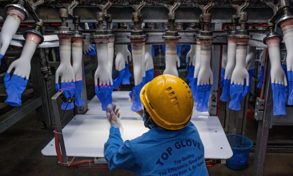 A worker inspects disposable gloves at the Top Glove factory production line.