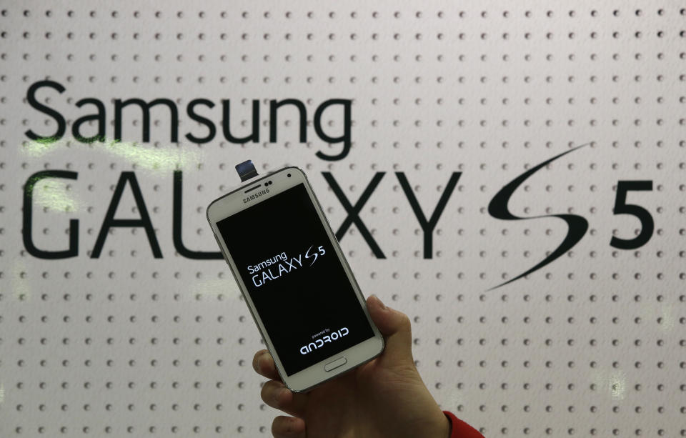 An employee shows Samsung's Galaxy S5 smartphone at a mobile phone shop in Seoul, South Korea, Thursday, March 27, 2014. The global launch of Samsung's latest smartphone is being upstaged by South Korean mobile network companies. SK Telecom, South Korea's largest mobile carrier, said it will start selling the Galaxy S5 on Thursday, two weeks before the scheduled sales launch on April 11. (AP Photo/Lee Jin-man)