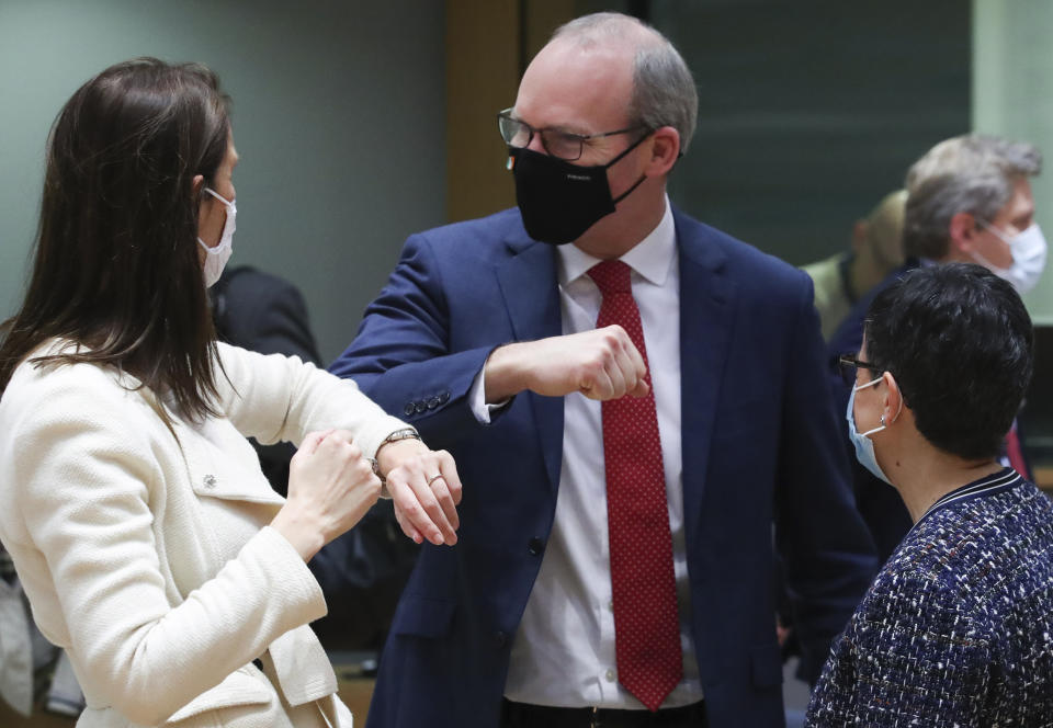 Belgium's Foreign Minister Sophie Wilmes, left, greets Ireland's Foreign Minister Simon Coveney, center, with an elbow bump during a meeting of EU foreign ministers at the European Council building in Brussels, Monday, Feb 22, 2021. European Union foreign ministers on Monday will look at options for imposing fresh sanctions against Russia over the jailing of opposition leader Alexei Navalny as the 27-nation bloc considers the future of its troubled ties with the country. (Yves Herman, Pool via AP)