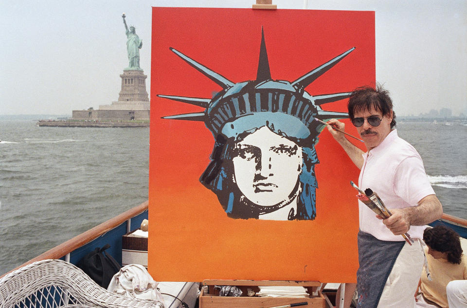 CORRECTS MARY MAX'S AGE TO 52, NOT 53 - FILE - In this July 4, 1987, file photo, artist Peter Max works on a painting of the Statue of Liberty aboard a boat in New York Harbor, as part of the Fourth of July festivities New York. Authorities say Mary Max, 52, the wife of the artist Peter Max, was found dead Sunday, June 9, 2019, in New York, of a suspected suicide amid a family fight over her husband’s work. Her death comes two weeks after The New York Times published a story detailing legal battles over the work of Peter Max, a prolific creator of colorful, psychedelic art who is now living with dementia at age 81. (AP Photo/David Bookstaver, File)